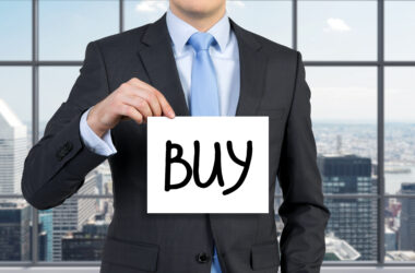 Mężczyzna trzymający kartkę z napisem "buy" jako symbol rekomendacji w tradingu